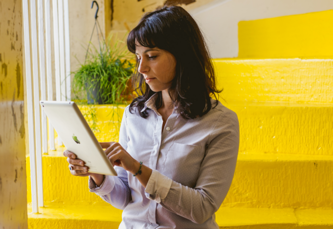 An image of woman using an iPad with yellow stairs in background.
