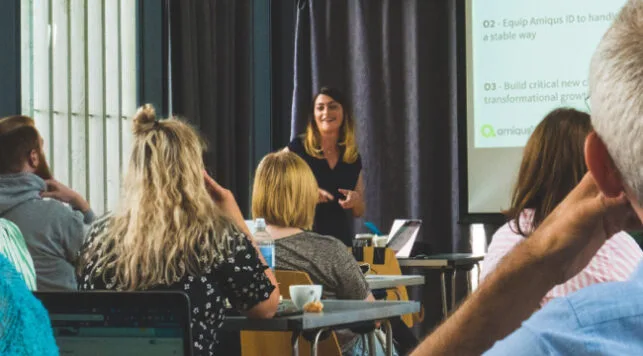 An image of the Amiqus team with a team member presenting a presentation from a projector.