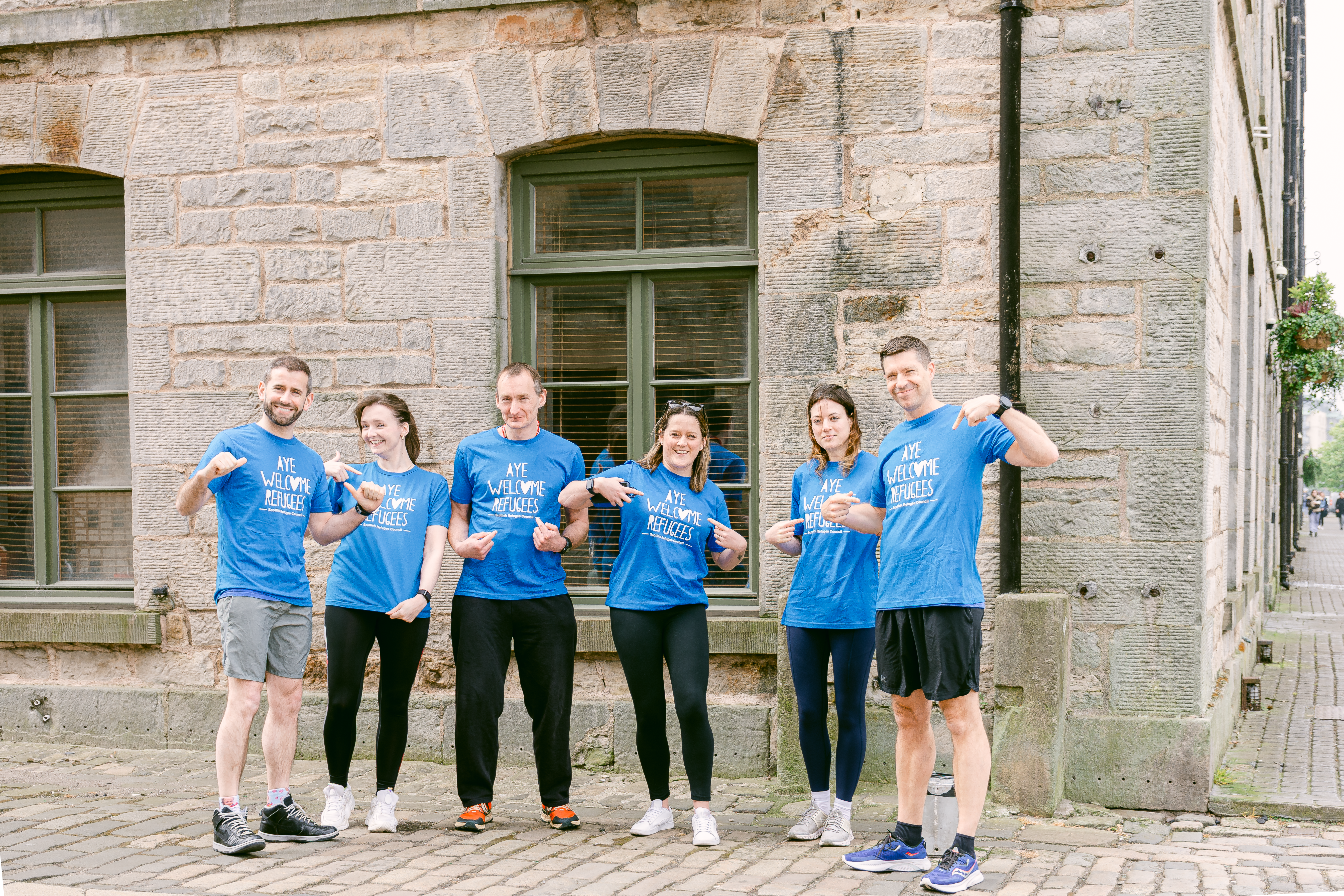 Amiqus team of runners participating in the Edinburgh Marathon Festival 2024 pose outside the Amiqus office in Leith, Edinburgh