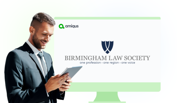 A man looking at a tablet in front of a coputer screen that says Birmingham Law Society along with the the Amiqus logo
